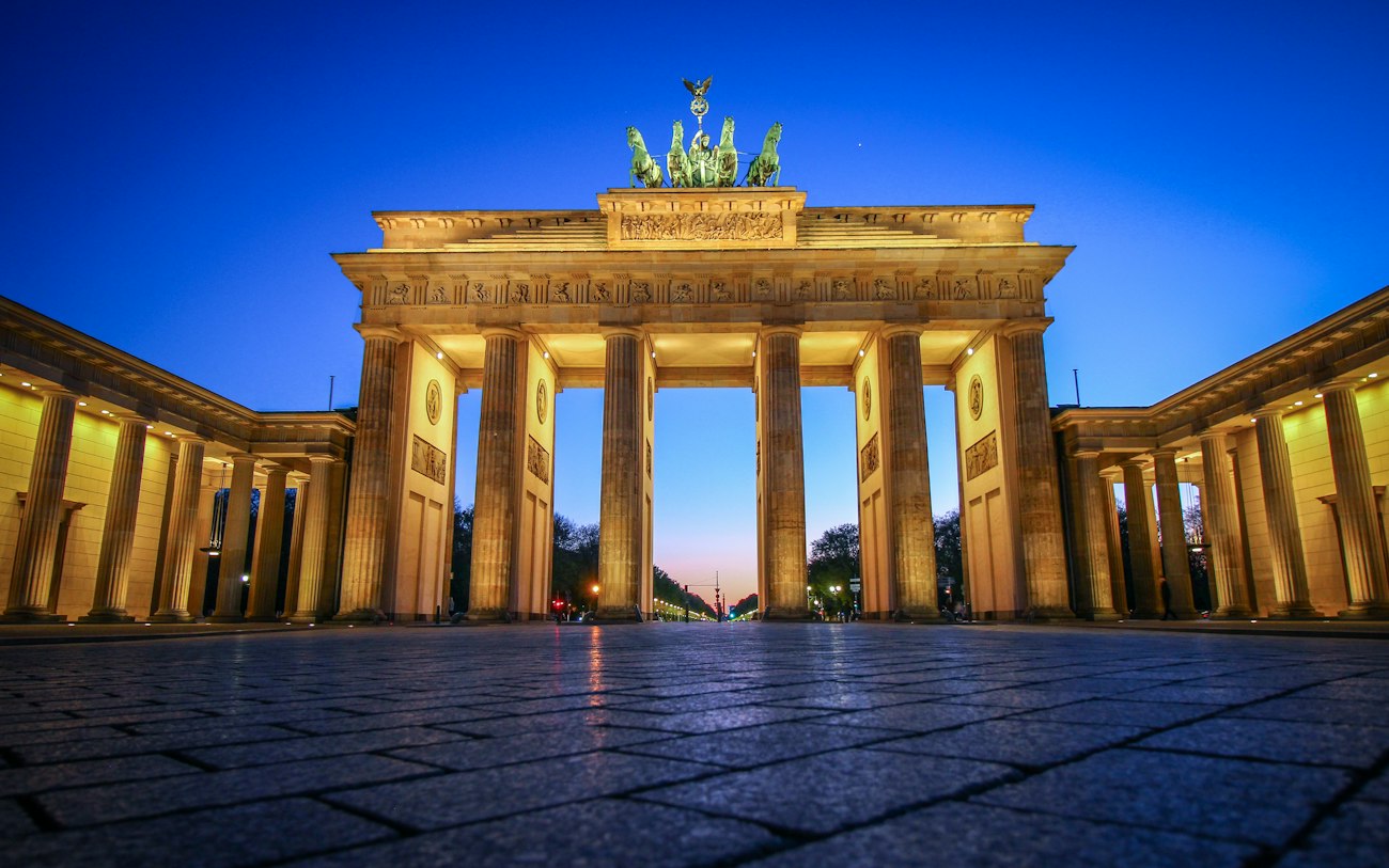Das nachts beleuchtete Brandenburger Tor vor klarem blauem Himmel in Berlin