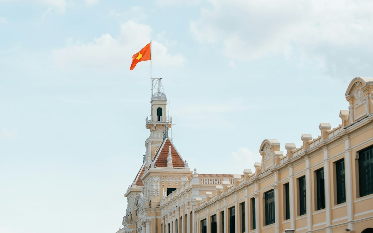 Vietnamesische Flagge auf einem prächtigen Gebäude vor blauem Himmel