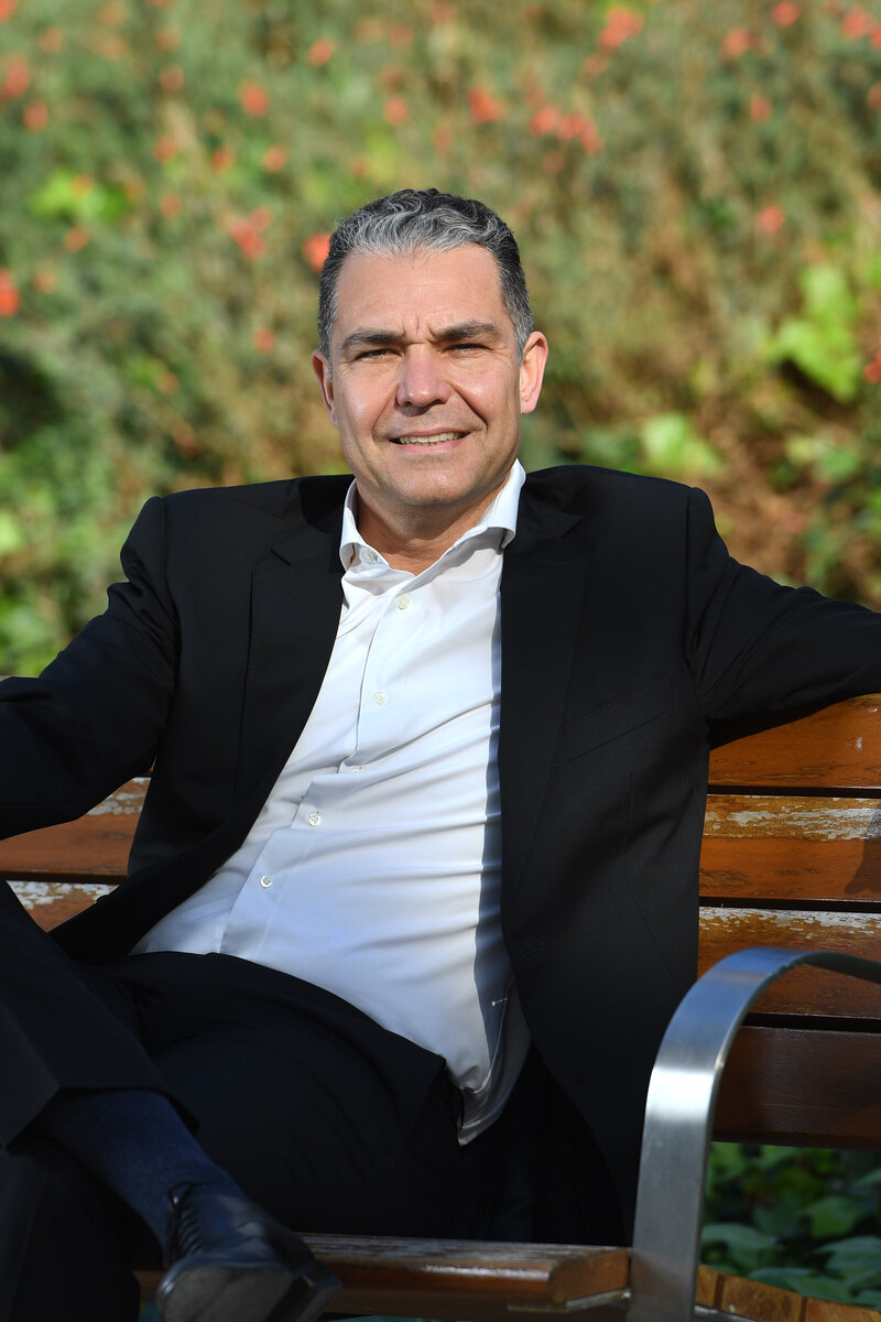 Aharon Acosta, founder of Expectat, seated on a park bench.