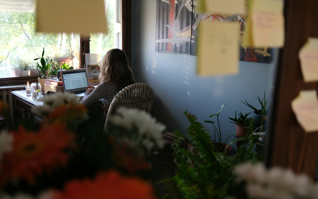 Woman working on laptop at a desk with plants