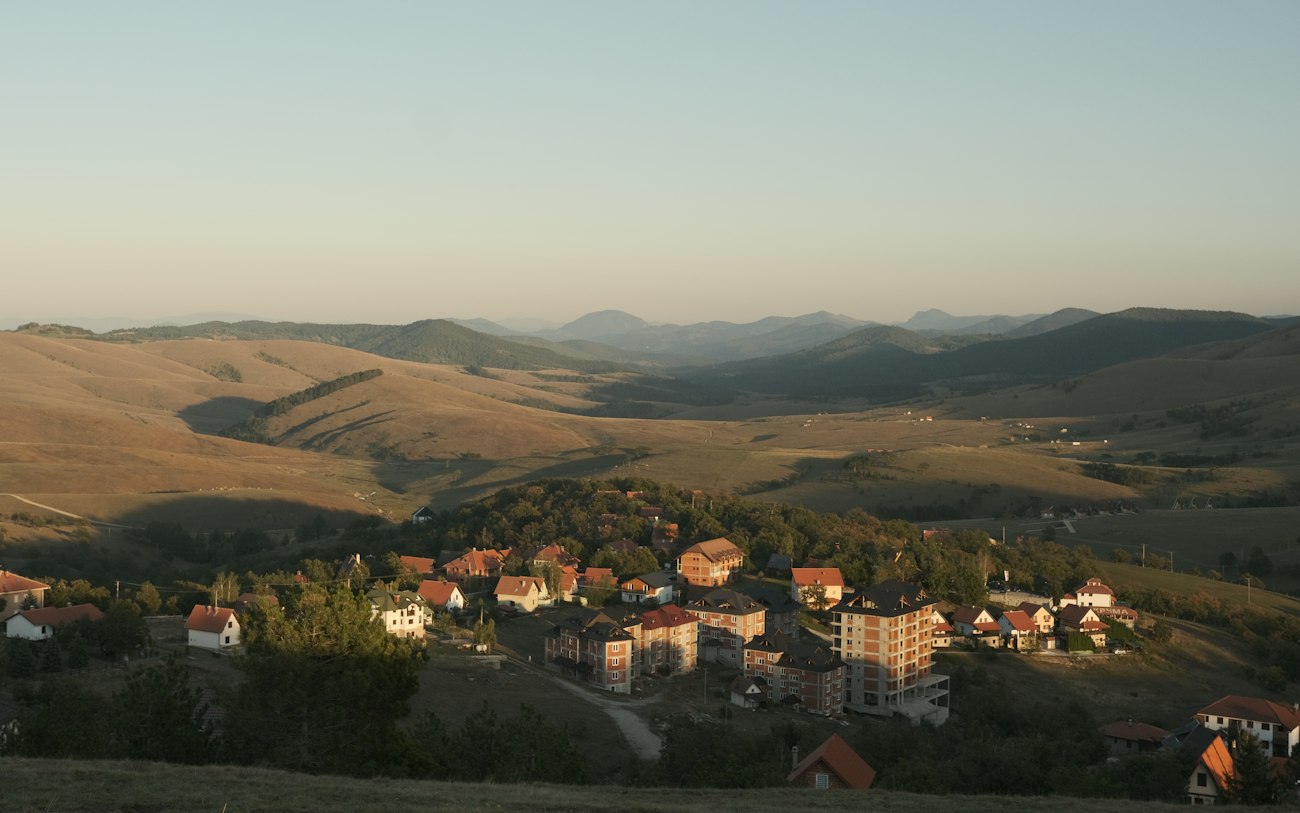 Ein Dorf liegt bei Sonnenuntergang am Fuß sanfter Hügel